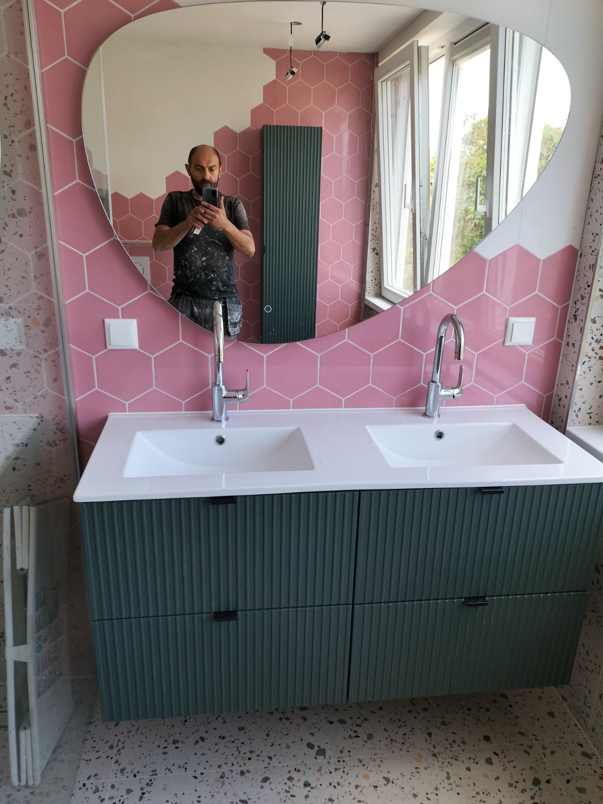 Badkamer met roze hexagon tegels, terrazzovloer en groen ribbelmeubel